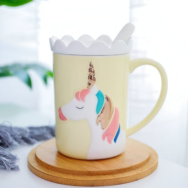 tasse-en-ceramique-licorne-1a.jpg Tasse jaune pâle avec couvercle décoré et motif licorne en relief. Une cuillère blanche repose sur le couvercle. Le tout est posé sur un sous-plat en bois., 45501199483135 | Licorne Shop