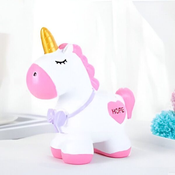Tirelire licorne blanche avec des accents roses et une corne dorée brillante. L'inscription "Hope" est visible sur un cœur rose sur le flanc. L'objet est placé sur une surface blanche, suggérant un décor de chambre d'enfant., 45501184770303 | Licorne Shop