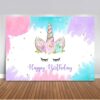 Une image d'arrière-plan de joyeux anniversaire de licorne. Il y a une licorne blanche avec une corne dorée et des fleurs roses, bleues et violettes sur la tête. Il y a aussi des étoiles dorées et des éclaboussures de peinture rose, violette et bleue sur le fond. Le texte "Happy Birthday" est écrit en lettres dorées avec un contour noir.