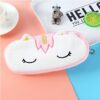 trousse-licorne-scolaire-2a.jpg Une trousse en peluche rose et blanche en forme de licorne avec des yeux fermés et une corne dorée.