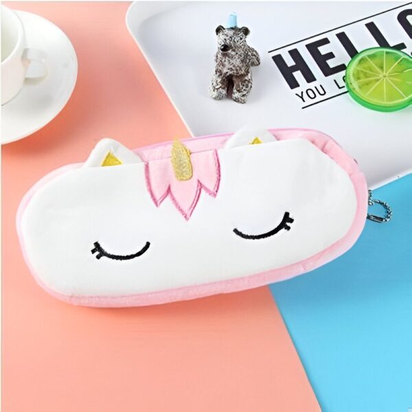 trousse-licorne-scolaire-2a.jpg Une trousse en peluche rose et blanche en forme de licorne avec des yeux fermés et une corne dorée.