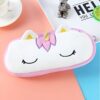 trousse-licorne-scolaire-4a.jpg Une trousse en peluche blanche et rose en forme de licorne avec des oreilles et une corne dorées et des yeux et des ailes roses.