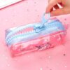 Une trousse transparente avec une fermeture éclair colorée et un motif de licorne rose.