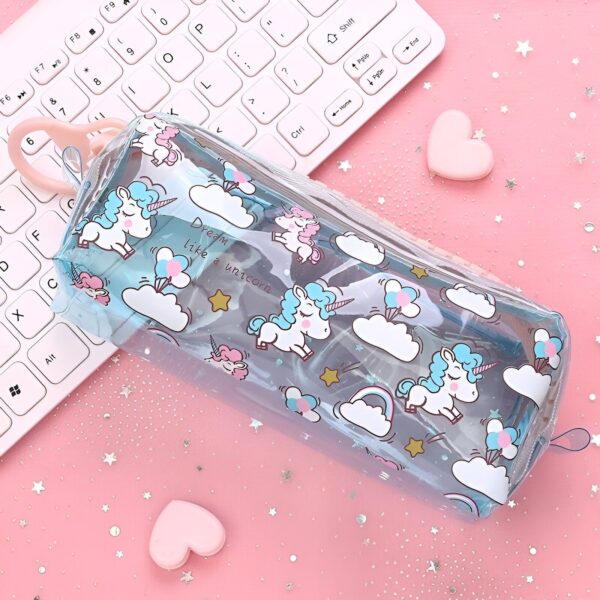 trousse-licorne-transparente-ecole-1a.jpg Une trousse transparente avec des licornes et des étoiles à l'intérieur. La trousse est posée sur un clavier d'ordinateur.