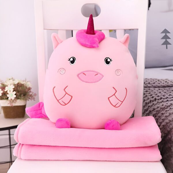 Coussin doux en forme de licorne rose avec une couverture assortie, posé sur une chaise blanche. Cadeau idéal pour enfants ou décoration de chambre. Confort et douceur garantis., 45501421715711 | Licorne Shop